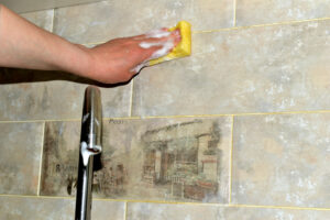 A woman washes ceramic tiles in the kitchen with a sponge.